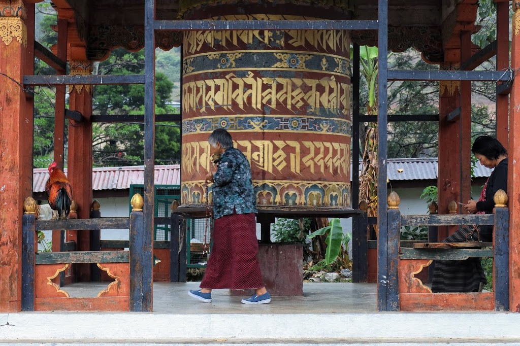 Image of a devotee chanting around a largeprayer wheel inside Khuruthang village monastery