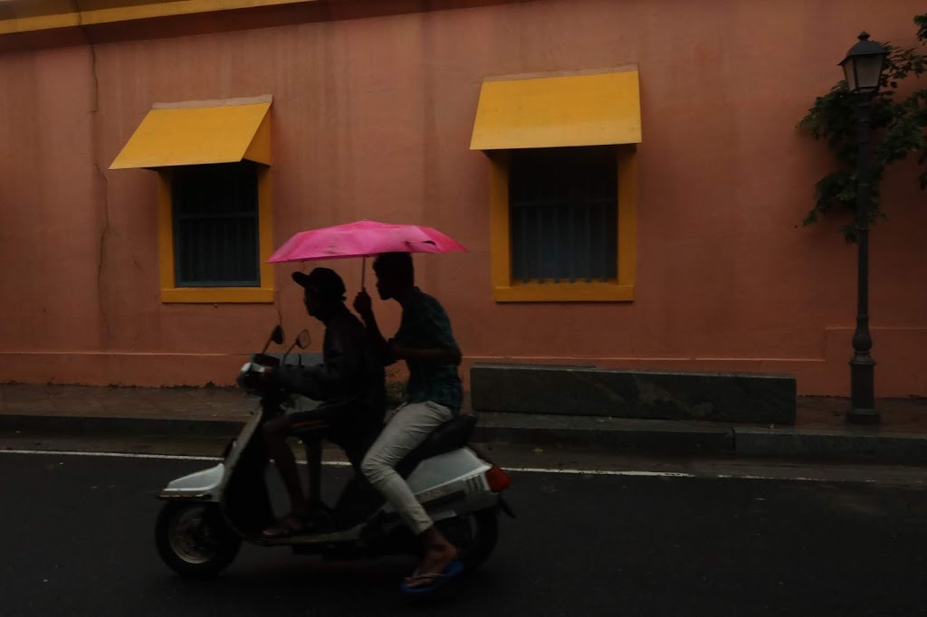 Image of two riders in front of a colourful exterior of an old French building in Pondicherry.