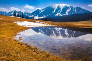 Reflection of snow capped mountains on a puddle of water in Doodhpathri in Kashmir